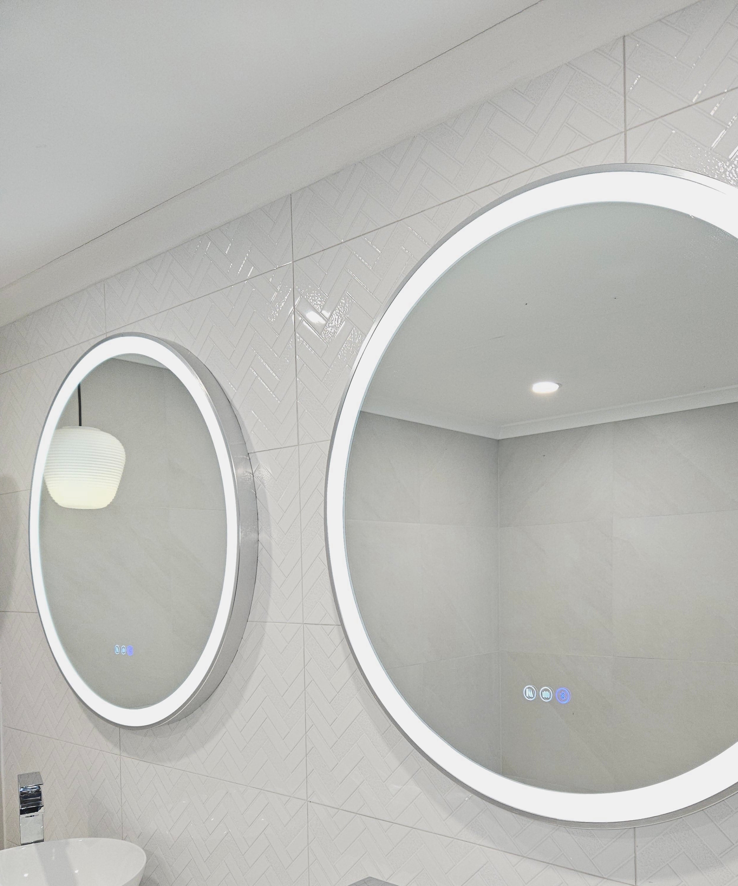 Side View of Two Silver Frame Circle Smart LED Mirrors in White-on-White Bathroom