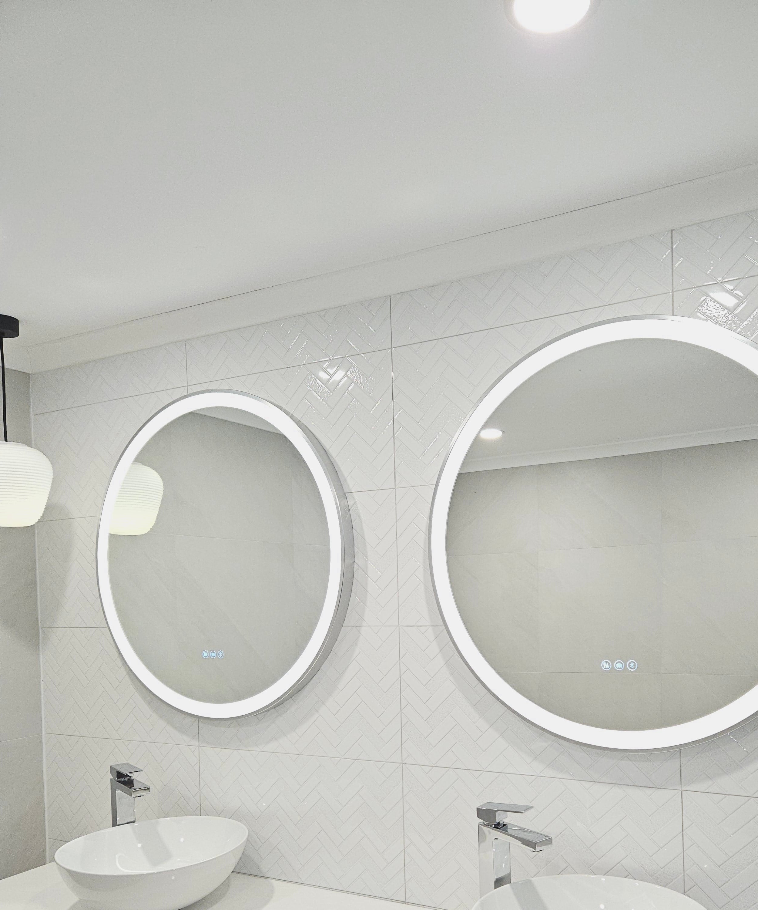 Two silver frame Smart Circle LED Mirrors on white bathroom with a pendant light and two white sink