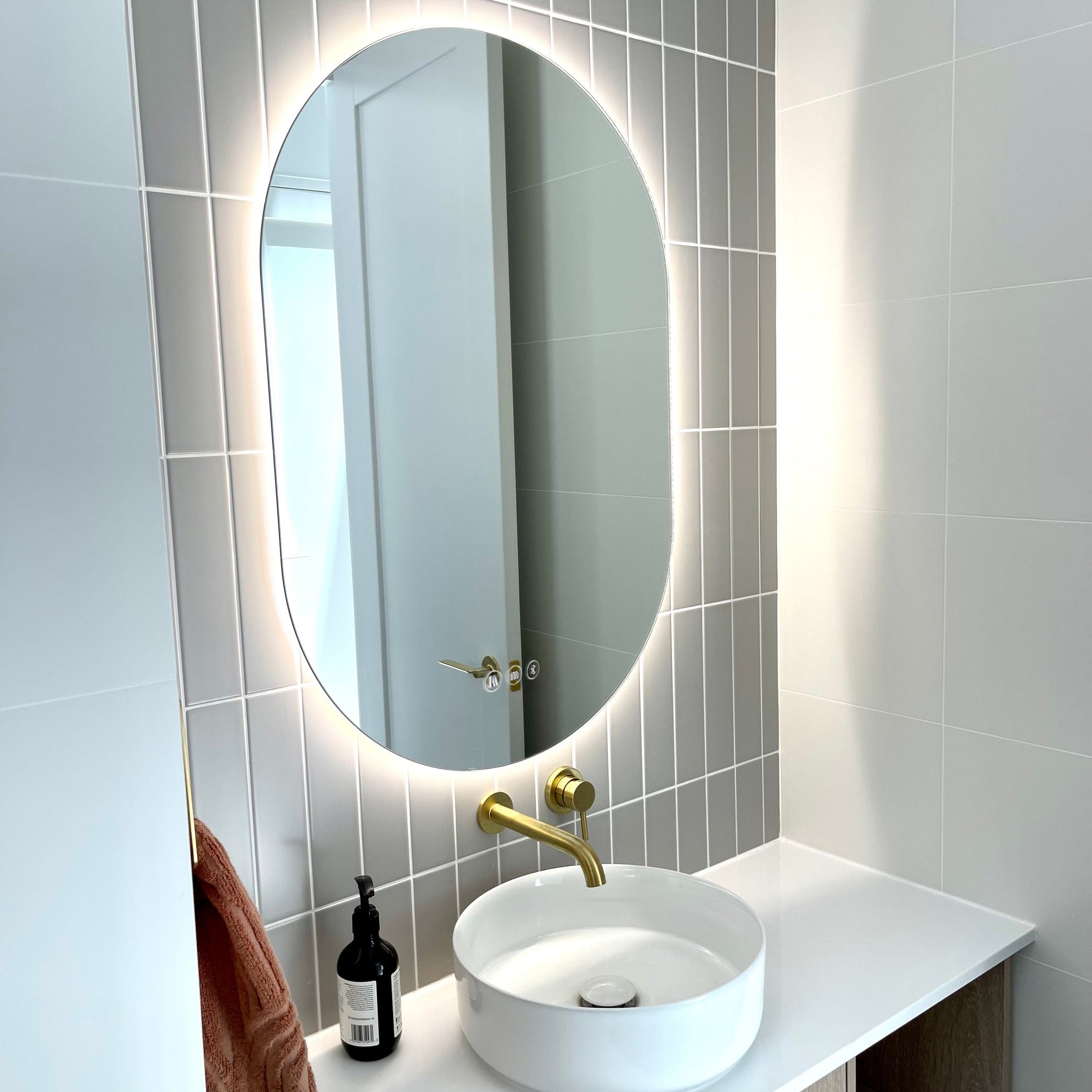 Neutral-Themed Powder Room with Well-lit Smart LED Mirror, Gold Faucet, White Sink, Wooden Cabinet