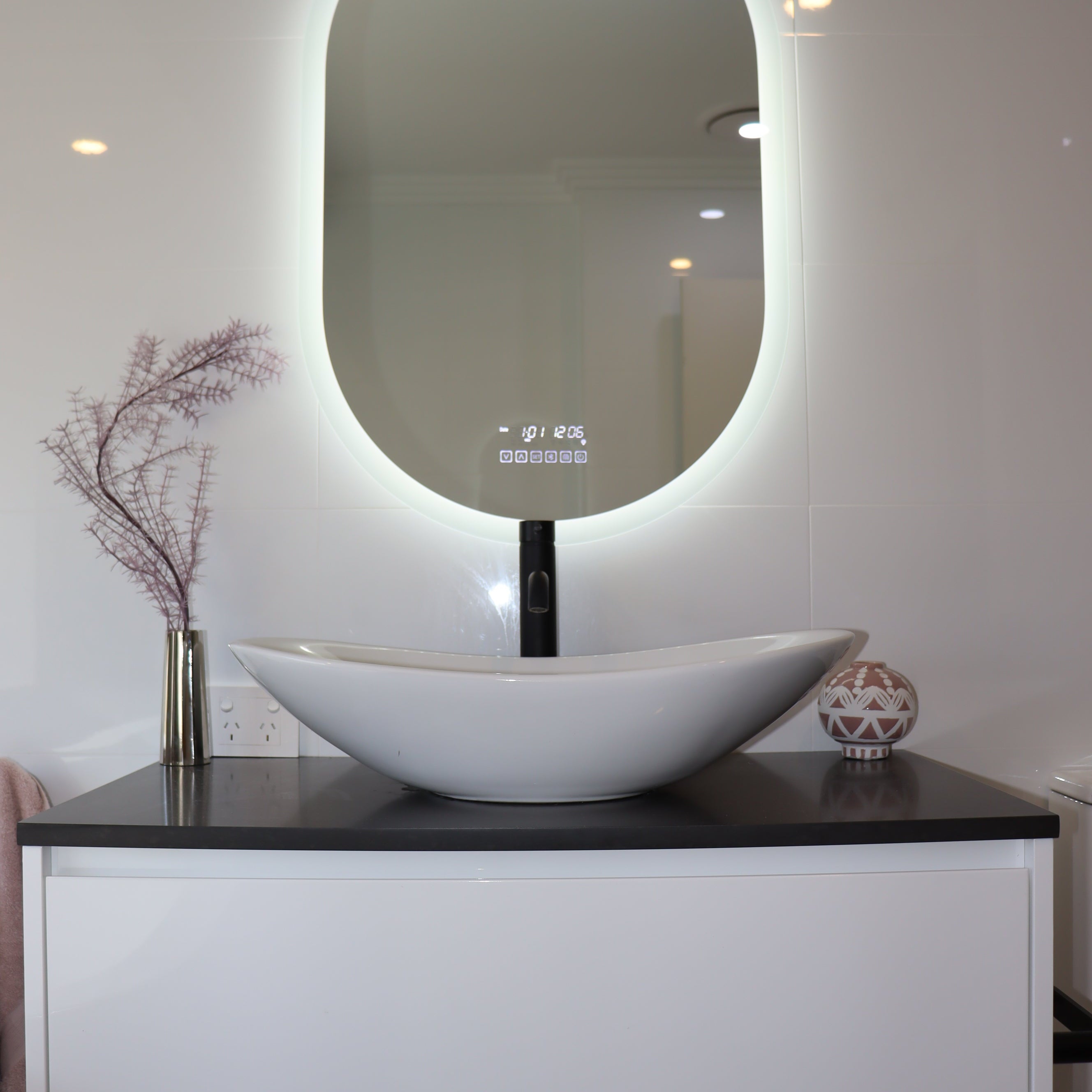 Pill-shaped Smart LED mirror radiating brilliant white backlit light in an all-white bathroom