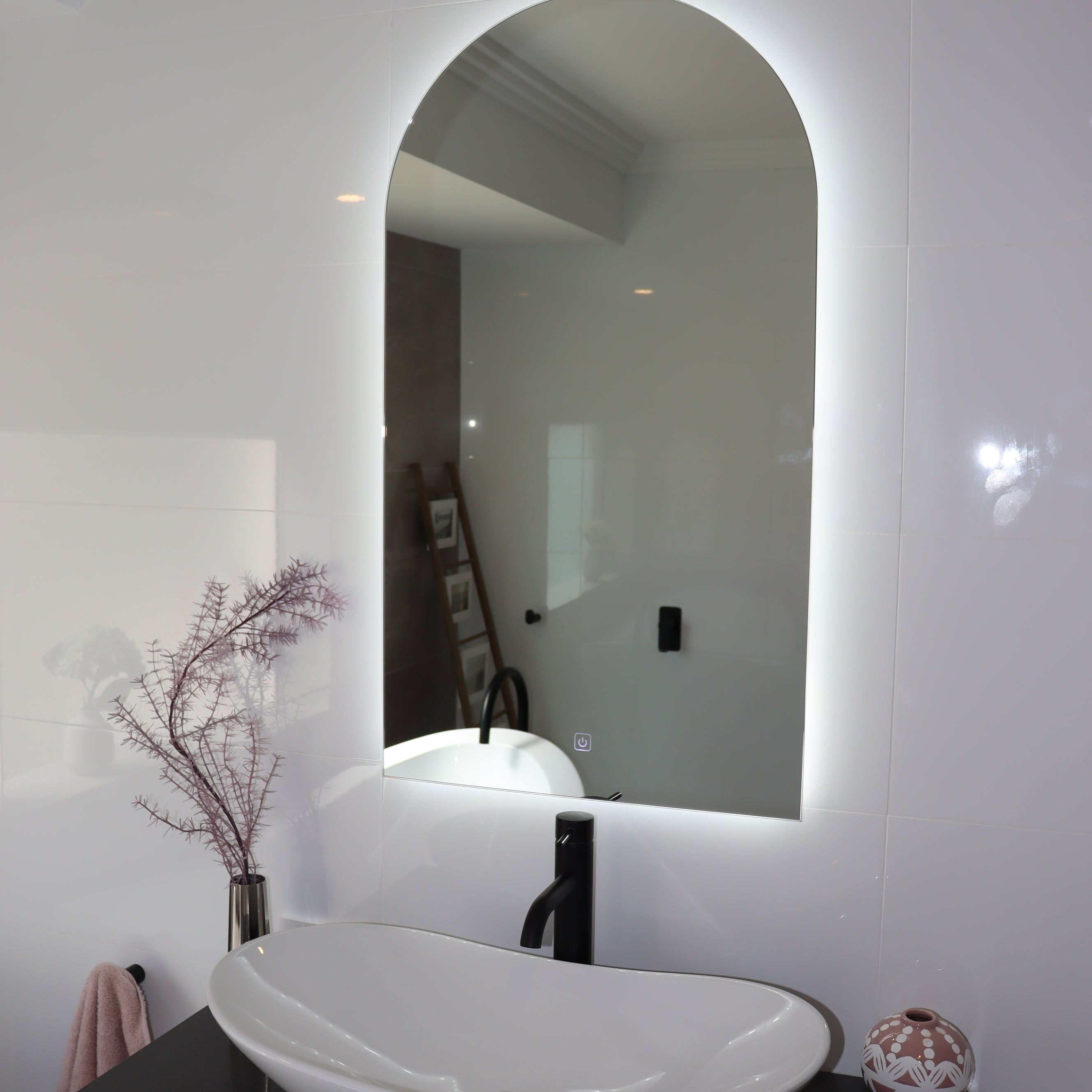 Elegant Curved LED Mirror Illuminating White Shiny Tiles and Black Countertop with White Vessel Sink