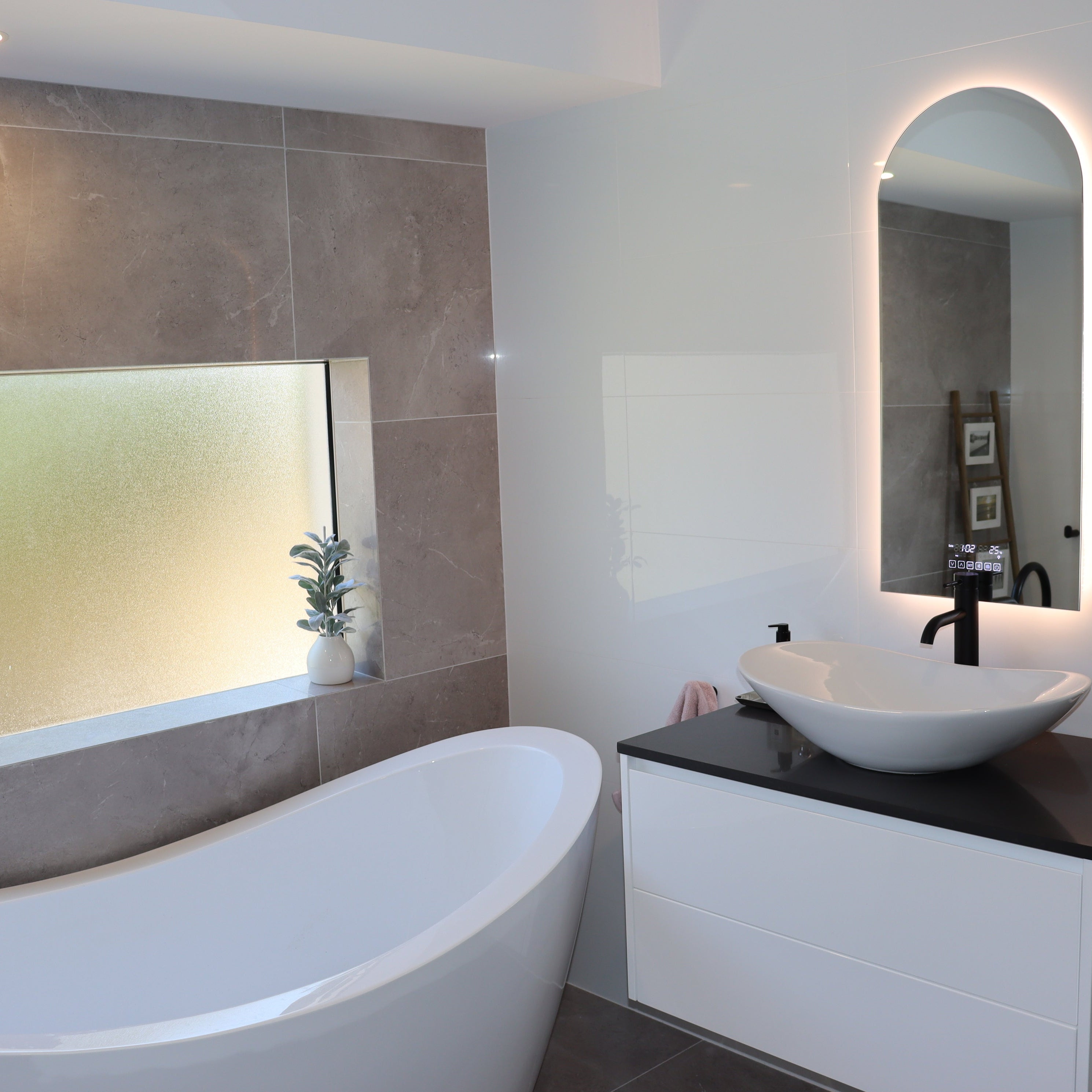 Split-design bathroom: Glossy white tiles, classy vanity, grey matte tiles, tinted window, bathtub.