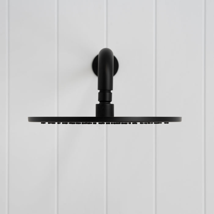 Bordeaux Wall Mounted Shower Head with Arm in Matte Black, front view on a white vertical-panelled wall