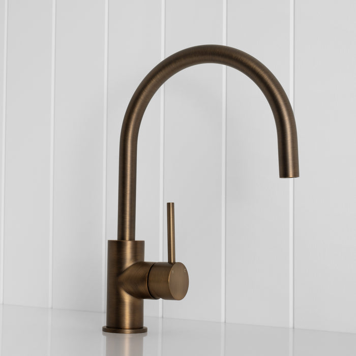 Como Kitchen Mixer Tap in Antique Brass, three-quarter front view on a white vertical-panelled wall