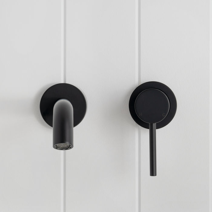 Milano Wall Spout Plus Wall Mixer in Matte Black, front view of spout and lever mixer on white vertical-panelled wall