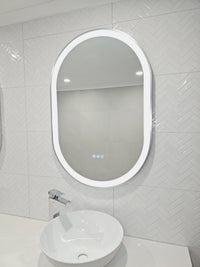 Oval Smart LED Mirror with Silver Frame and Triple-Touch Buttons in Couple's White-on-White Bathroom