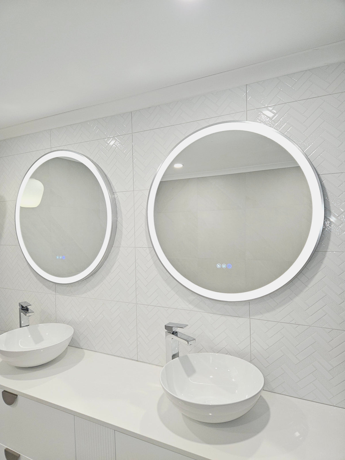 Doorway View of Two Silver Frame Circle Smart LED Mirrors in Couple's White-on-White Bathroom