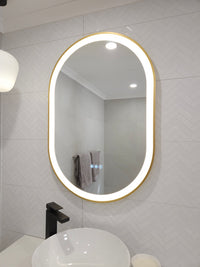 Gold-framed Oval Smart Mirror with White LED Light in White Powder Room