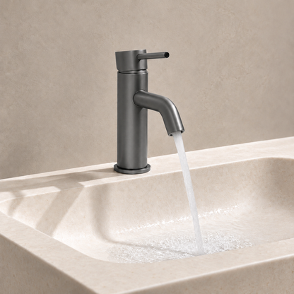 Vienna Short Basin Mixer in Brushed Gunmetal, water flowing from the spout into a beige stone basin