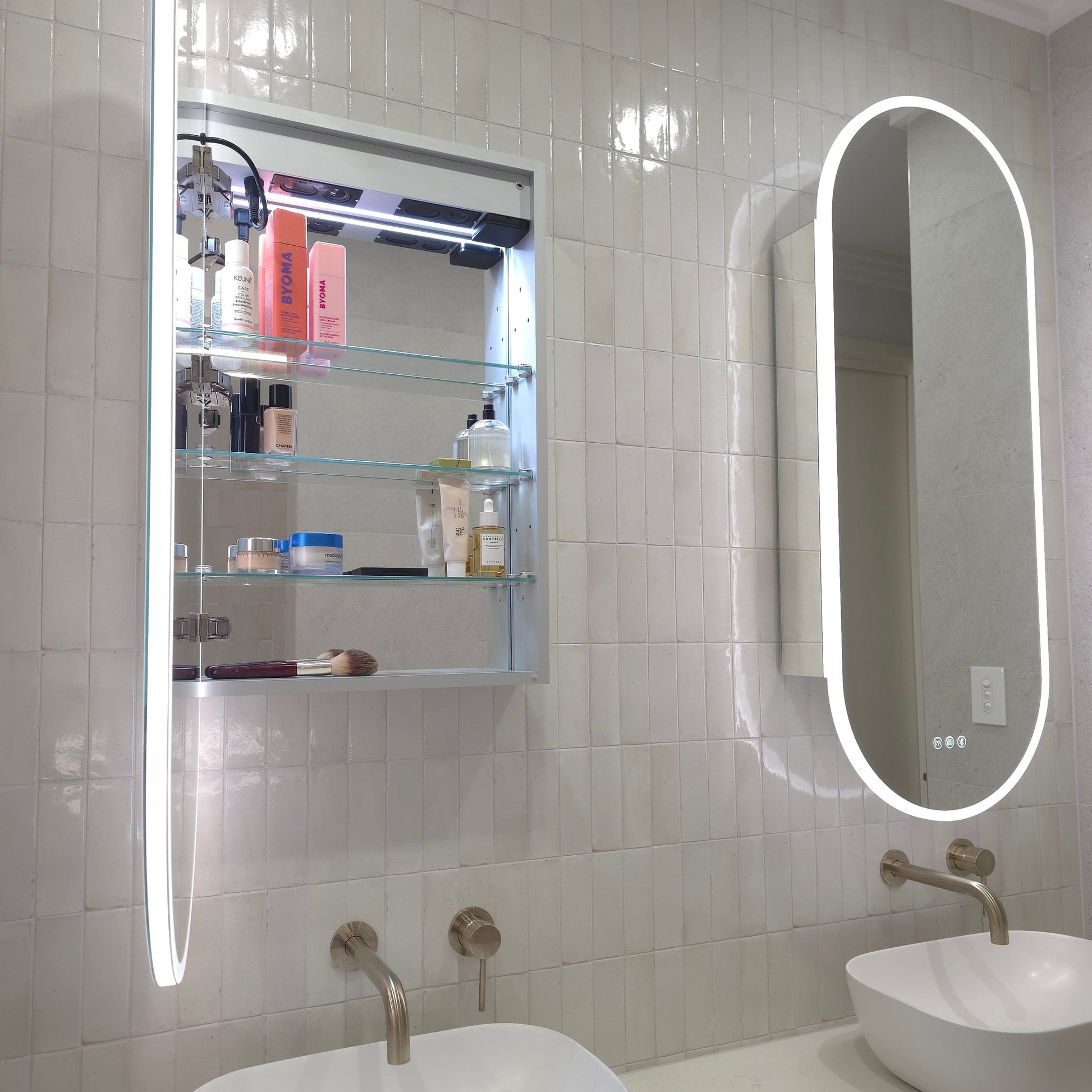 Frameless LED mirror cabinet showing adjustable internal storage shelves and bluetooth speakers