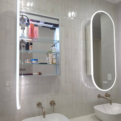 Frameless LED mirror cabinet showing adjustable internal storage shelves and bluetooth speakers