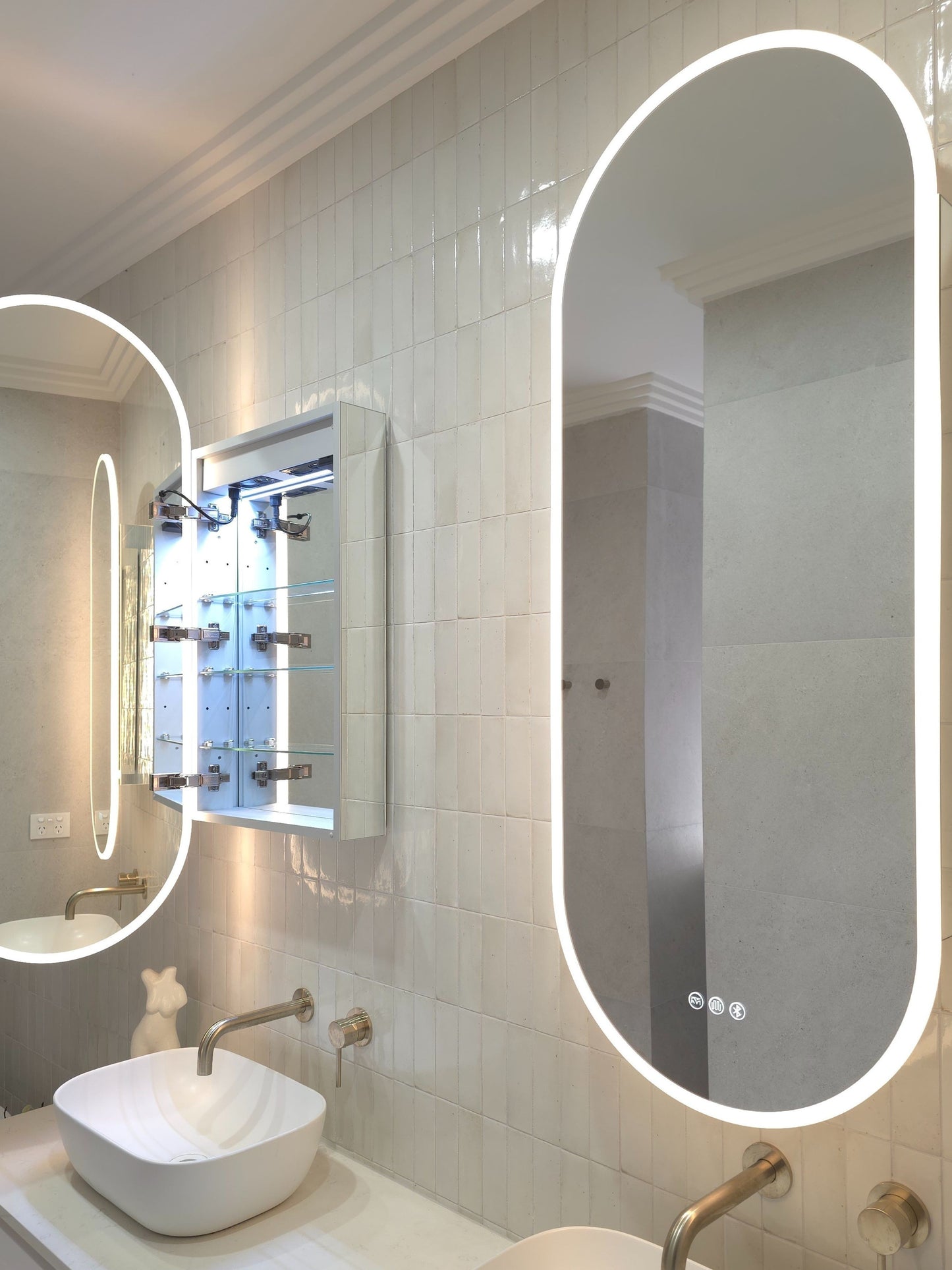 Frameless oval LED mirror cabinet showing internal storage and bluetooth speakers