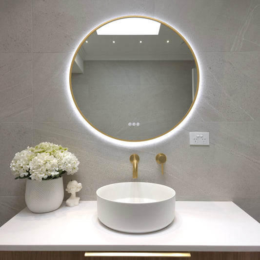 Bellagio round backlit LED mirror with a gold wrap-around frame above a round basin with brushed brass tapware