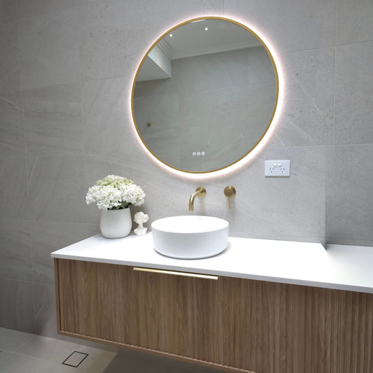 Bellagio round LED mirror with a gold frame above a timber wall-hung vanity, wider room view