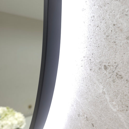 Close-up of the Bellagio matte black frame edge, which wraps around the glass, with the LED halo on speckled tiles