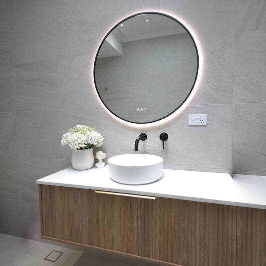 Bellagio round LED mirror in Matte Black above a timber wall-hung vanity, wider room view