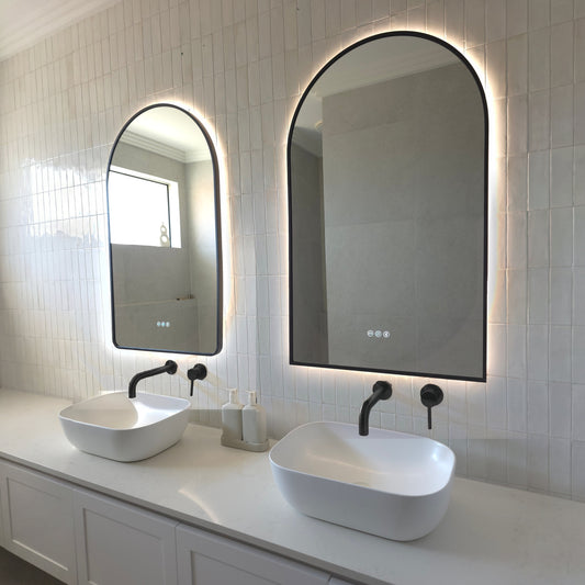 Two Calais arch-shaped LED mirrors with matte black frames above twin vessel basins with matte black tapware