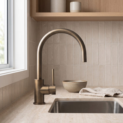 Como Kitchen Mixer Tap in Antique Brass, at a stainless sink with oat stacked tiles and an oak shelf above
