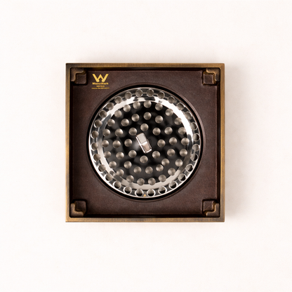 Granada Tile Insert Floor Waste in Antique Brass, cover removed to show the round strainer on a plain white background