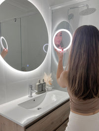Lipstick touch-up: Girl using small circle LED mirror, with big Circle LED Mirror in white bathroom