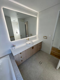 Corner View of White & Light Brown Themed Powder Room with Wall-to-Wall Smart LED Mirror