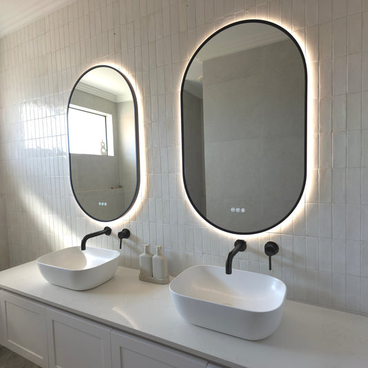 Two Marseille pill-shaped LED mirrors with matte black frames above twin vessel basins with matte black tapware