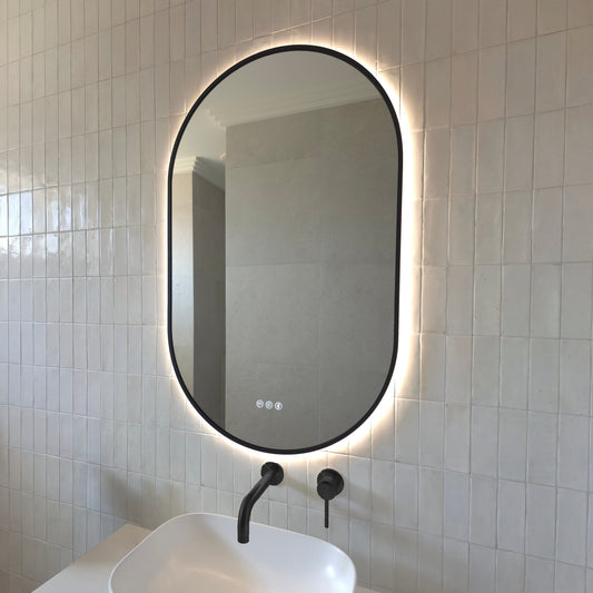 Marseille pill-shaped backlit LED mirror in Matte Black above a vessel basin with matching Matte Black tapware