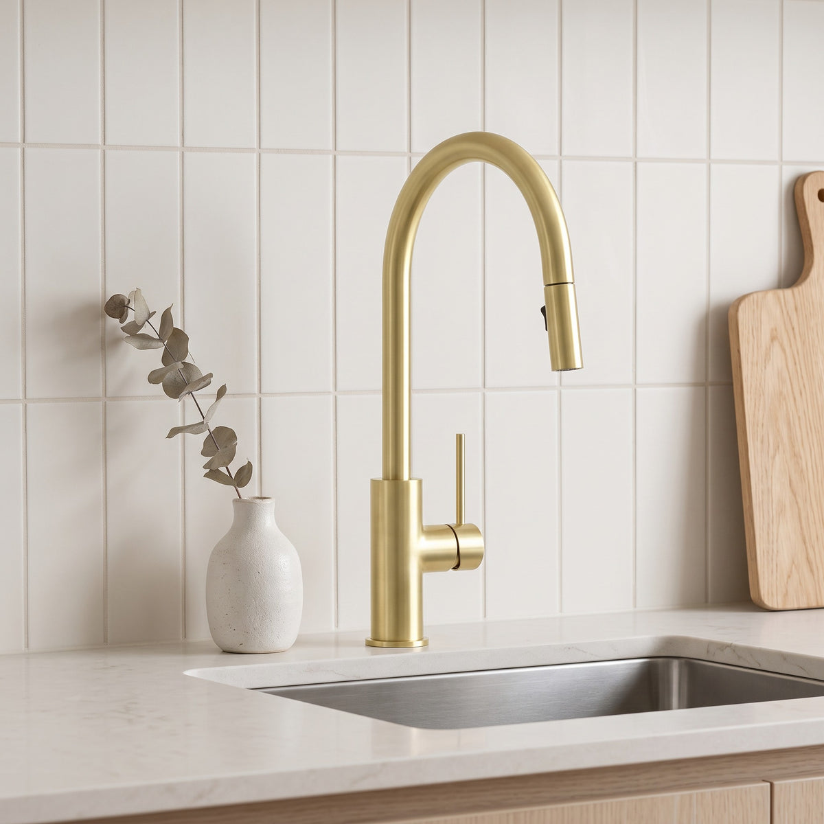 Porto Pull-Out Kitchen Mixer in Brushed Brass, at a stainless sink with warm-white vertical tiles and an oak board