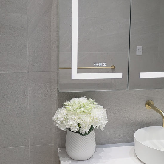Frameless LED mirror cabinet showing internal storage and lighting