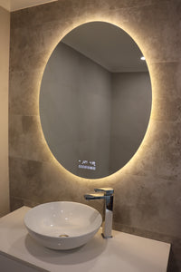 Oval Smart LED Mirror in Yellow Light Mode on Beige with Grey Tiled Wall, White Countertop, and Sink