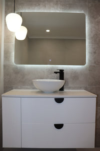lit pendant light and Backlit LED mirror mounted on greyish-brown tiles above floating white cabinet