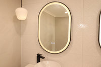 Oval Smart LED Mirror with Black Frame in Cream-Themed Powder Room, Complemented by Black Accents