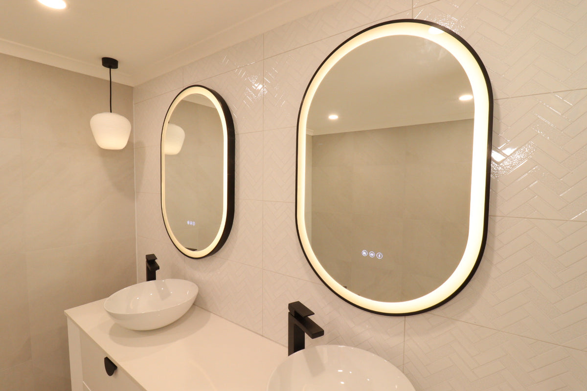 Right-side view of two pill-shaped Smart LED mirrors in a cream-colored bathroom with black accents