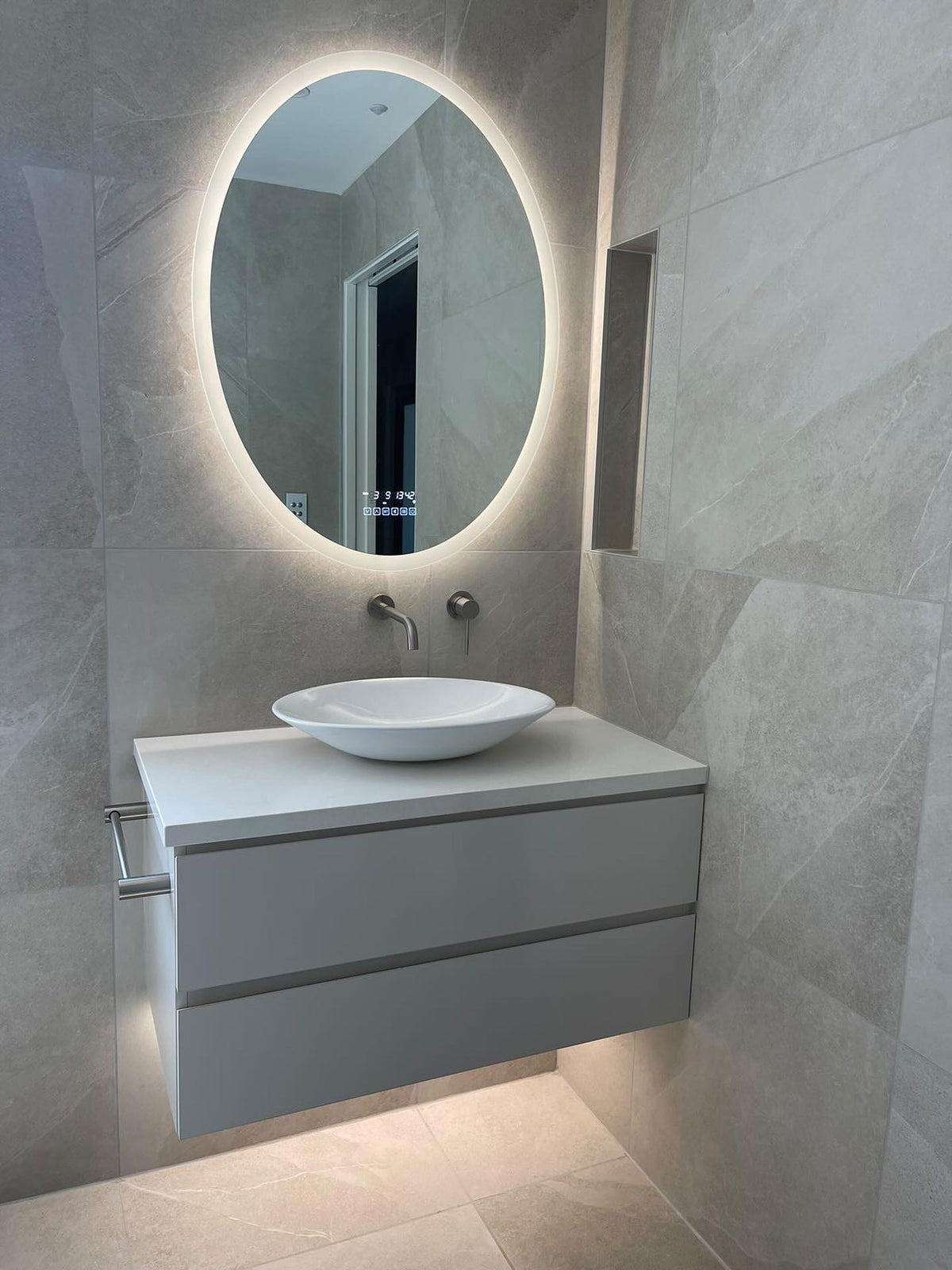 Oval Smart LED Mirror on a warm white mode in a beige and white theme bathroom