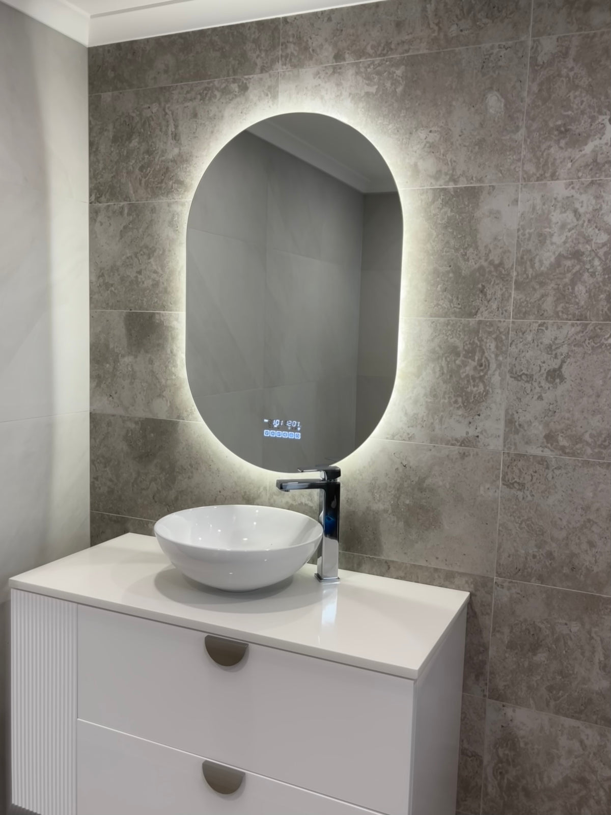 Oval Smart LED Mirror in a Neutral Earthy Washroom with Greyish-brown Dirt-like Tiles
